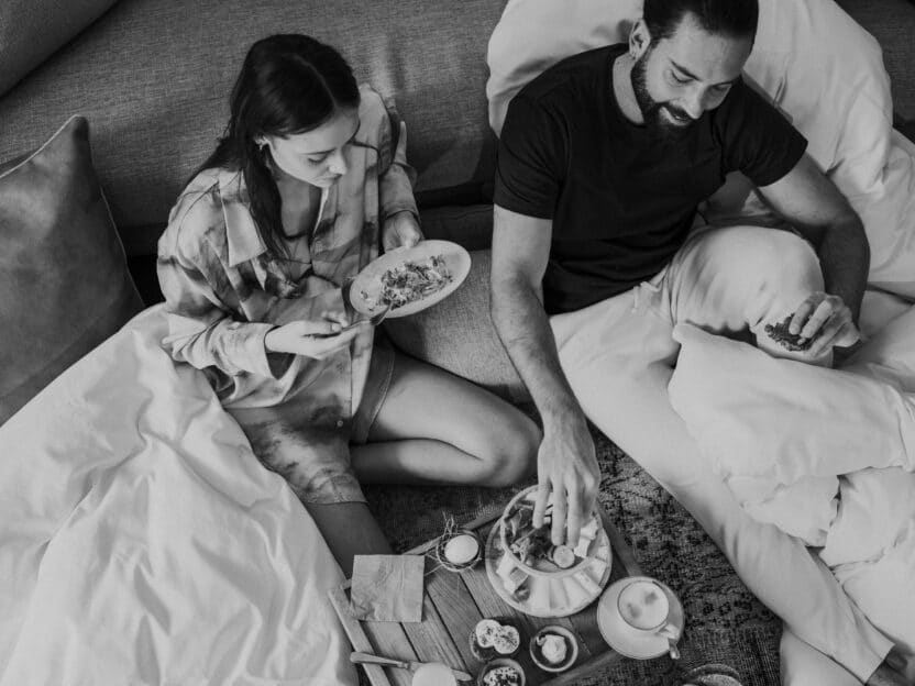 Frau und Mann im Bett am Frühstücken
