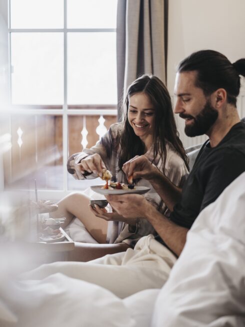 Mann und Frau im Bett am Frühstücken